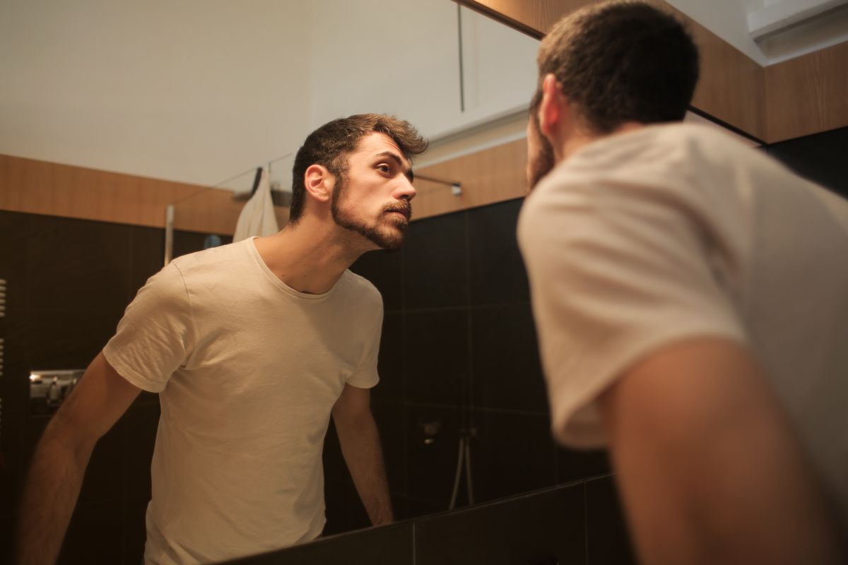 鏡で頭部を確認する男性