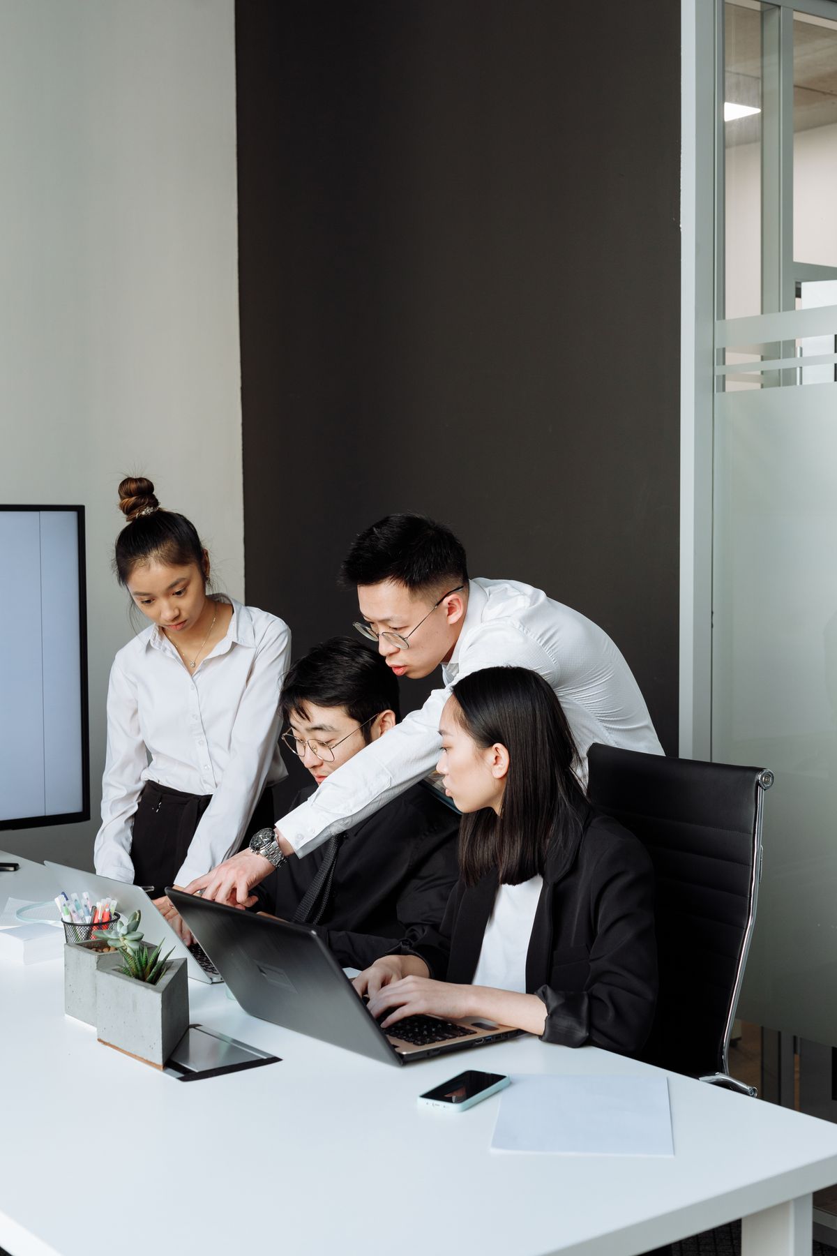 ノートパソコンを見ながら話し合う人たち
